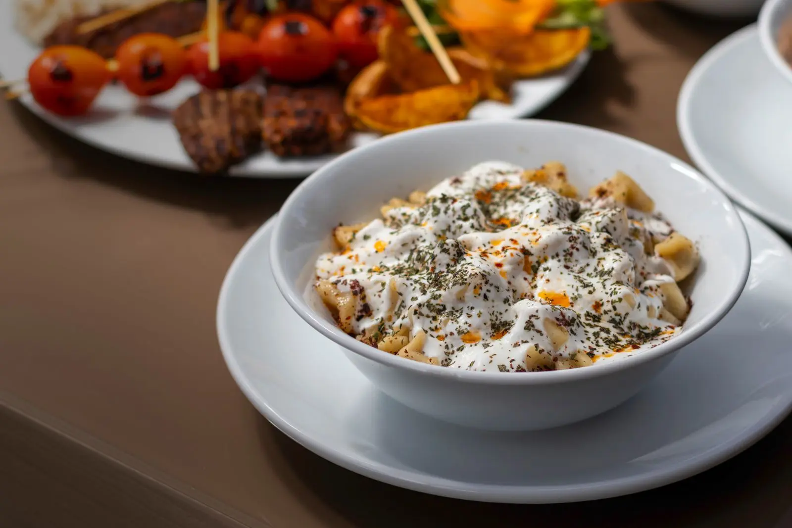 Mantı servis avec yaourt, herbes et beurre chaud parfumé.